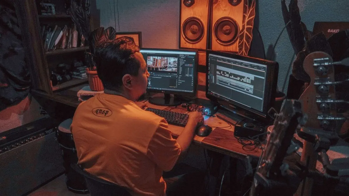 Mesa de edición de vídeo con dos monitores mostrando una línea de tiempo de montaje