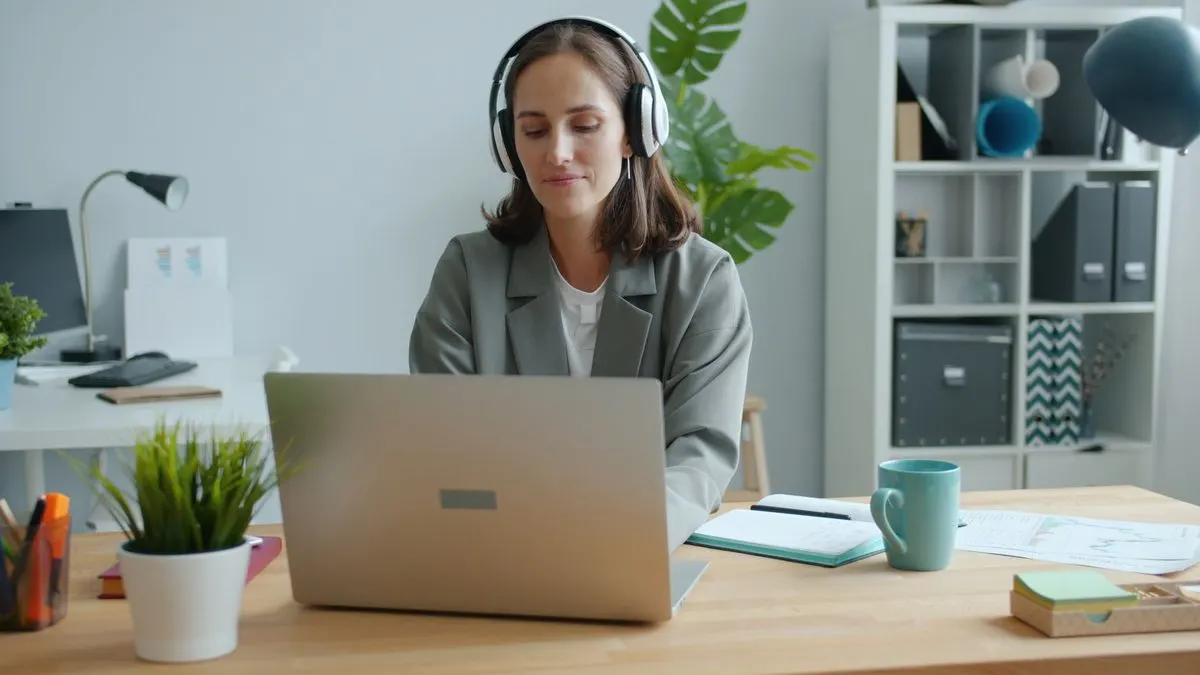 Persona siguiendo una formación en línea con portátil y auriculares en una oficina