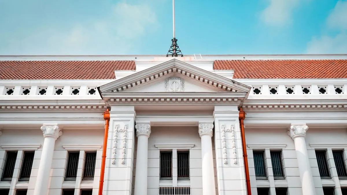 Fachada neoclásica de un edificio institucional con columnas blancas bajo un cielo azul