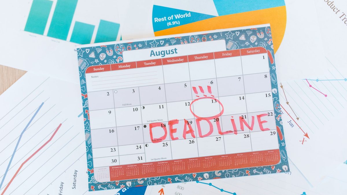 Calendario de sobremesa con una fecha límite marcada en rojo junto a gráficos y documentos