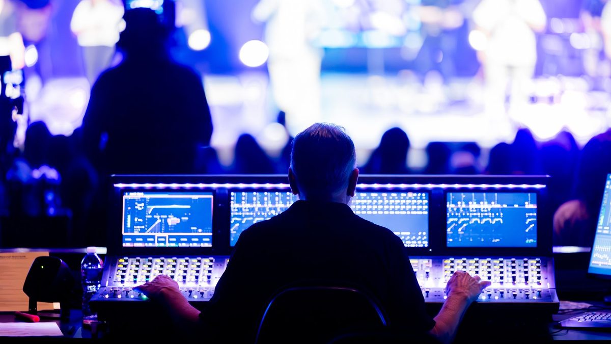 Técnico de sonido manejando una mesa de mezclas digital durante un directo