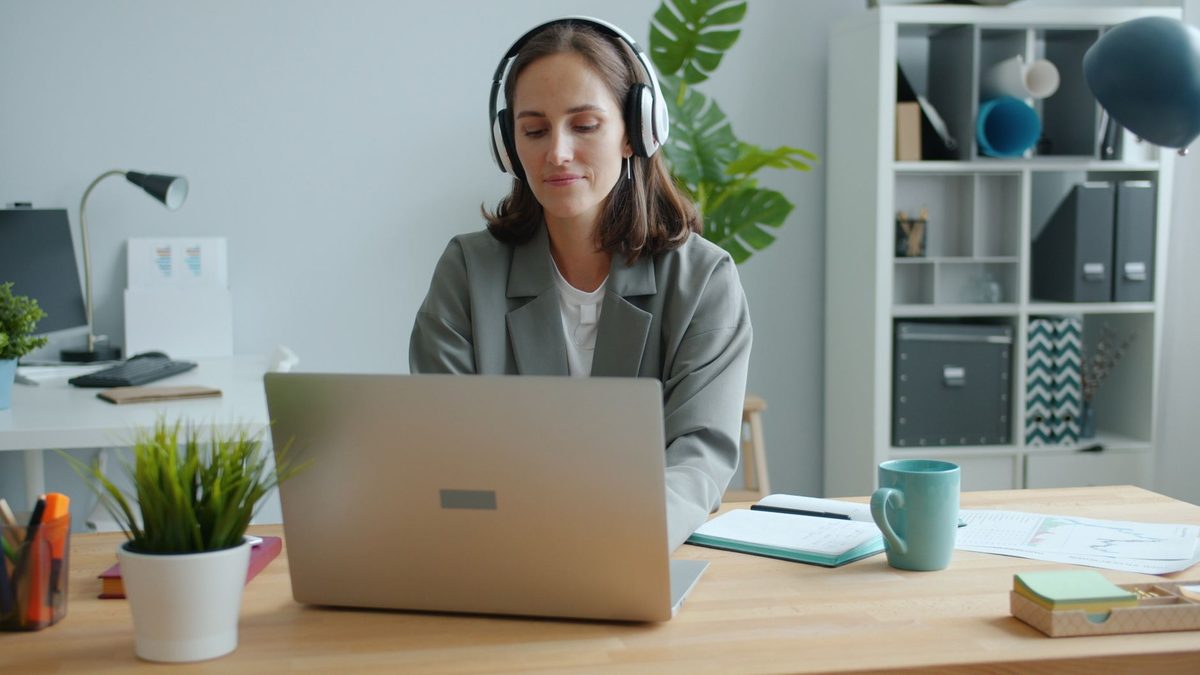 Persona siguiendo una formación en línea con portátil y auriculares en una oficina